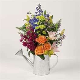 Mixed bouquet in a silver watering can with orange roses and lilies