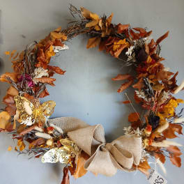 Autumn wreath with orange leaves, dried flowers, and a burlap bow