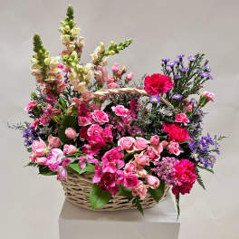 Basket arrangement of pink flowers with purple accents