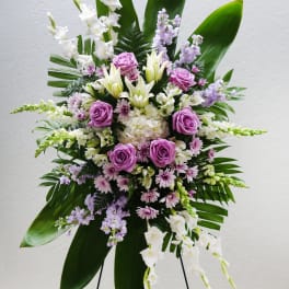 Standing floral spray with purple roses, white lilies, and lavender blooms