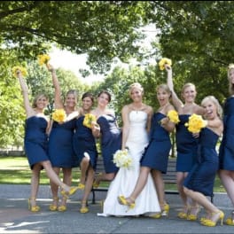 Bride with bridesmaids holding yellow bouquets outdoors