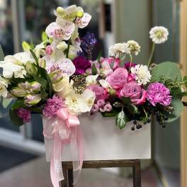 Pink and white floral arrangement in a white box with a ribbon