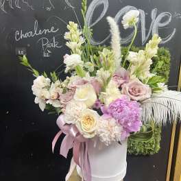 Pink and white floral arrangement in a white hatbox with ribbon