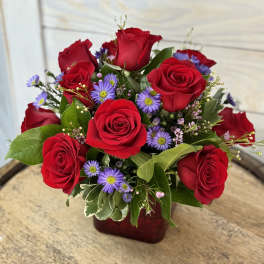 Red roses and purple daisies in a red vase