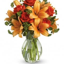 Orange lilies and red roses in a clear glass vase