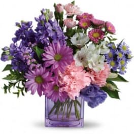 Purple and pink mixed bouquet in a square glass vase