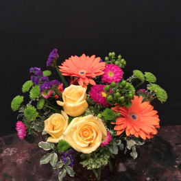 Bouquet of yellow roses, orange gerbera daisies, and purple accents