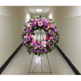 Large circular floral wreath on a metal stand with pink and purple roses