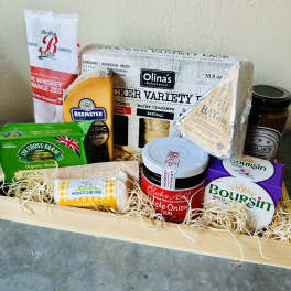 Assorted cheeses, crackers, salami, and jam in a wooden gift tray