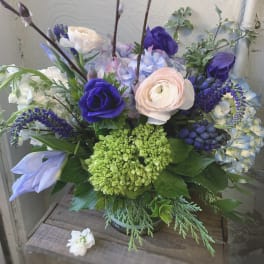 Bouquet of purple, blue, and blush flowers in a glass vase