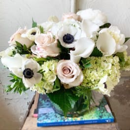 White and blush bouquet with roses, calla lilies, and anemones in a glass vase