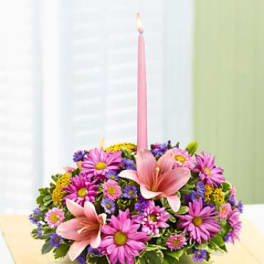 Pink and purple flower arrangement with a tall pink candle