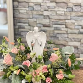 Pink rose arrangement with a white angel figurine centerpiece