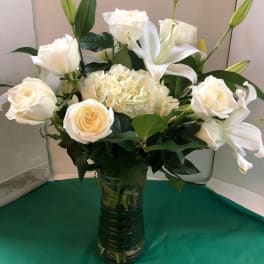 White roses and lilies arranged in a glass vase