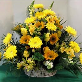 Yellow and orange mixed flower arrangement in a white basket