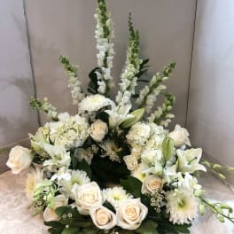 White floral arrangement with roses, lilies, and tall snapdragons
