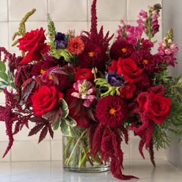 Red roses and burgundy dahlias in a clear glass vase