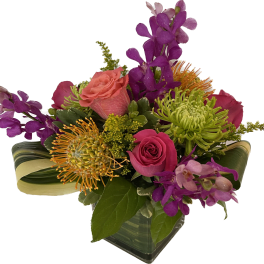 Mixed bouquet with pink roses, green spider mums, and purple orchids in a glass vase