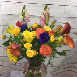 Mixed bouquet with roses, calla lilies, and snapdragons in a glass vase