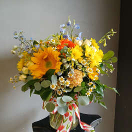 Bright mixed bouquet in a glass vase with sunflowers and daisies