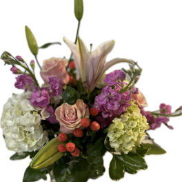 Pink lilies, roses, hydrangeas, and purple blooms in a bouquet