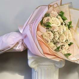 Bouquet of pale pink roses wrapped in pink and gold paper