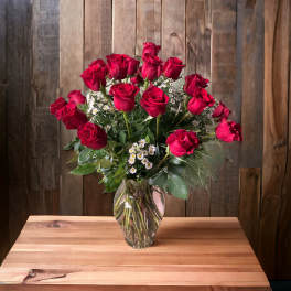 Bouquet of red roses with small white filler flowers in a clear glass vase