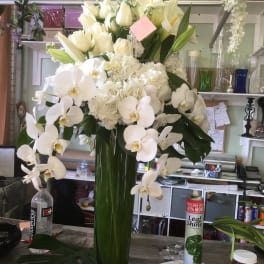 White orchids and lilies arranged in a tall green vase