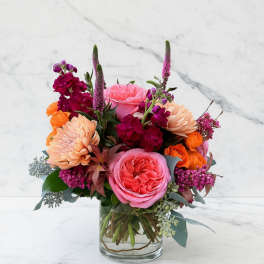 Pink and orange mixed flower arrangement in a clear glass vase