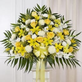 Yellow and white floral standing spray with a ribbon bow