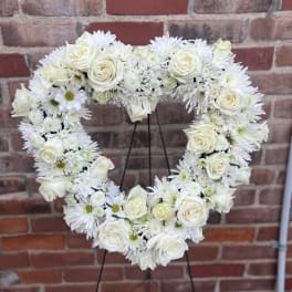 Heart-shaped white floral wreath on a stand