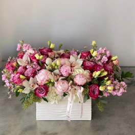 Pink and white floral arrangement in a white box with ribbon