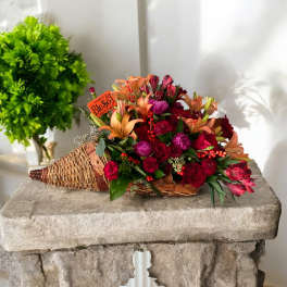 Basket arrangement with red and orange flowers and a small thank-you sign