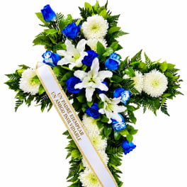 Cross-shaped floral spray with white lilies, white chrysanthemums, and blue roses