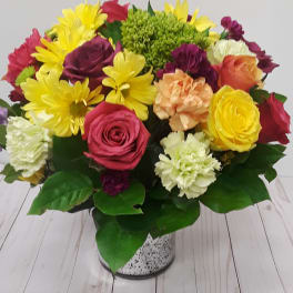 Mixed bouquet of roses, daisies, and carnations in a speckled vase