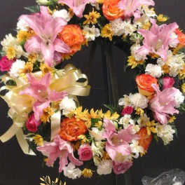 Heart-shaped floral wreath with pink lilies, orange roses, and white daisies