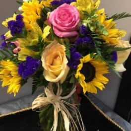 Bouquet of pink and peach roses with yellow sunflowers and purple filler flowers
