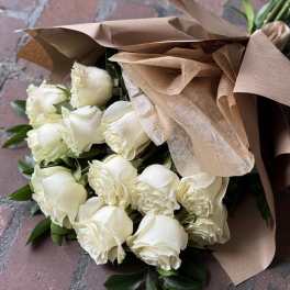 Bouquet of white roses wrapped in brown paper