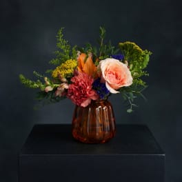 Mixed flower arrangement in an amber glass vase