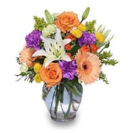 Mixed bouquet with orange roses, white lilies, and purple flowers in a glass vase