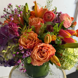 Colorful bouquet of roses, tulips, lilies, and hydrangeas in a green vase