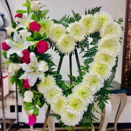 Heart-shaped floral wreath with white chrysanthemums and red roses on an easel