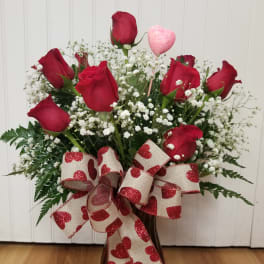 Bouquet of red roses with baby's breath in a vase and heart ribbon
