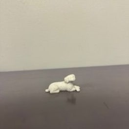 Small white plush dog lying on a dark surface