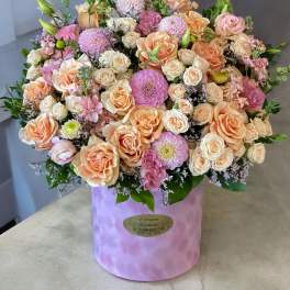 Large pastel bouquet of roses and pink blooms in a lavender hat box