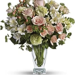 Pink roses and white flowers arranged in a clear glass vase