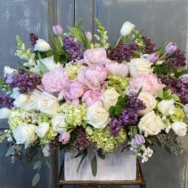 Large pastel floral arrangement with pink and white roses in a white container