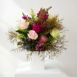 Mixed bouquet of pink and green flowers in a white vase