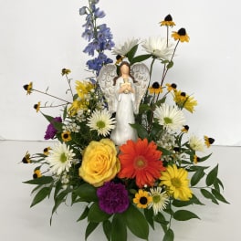 Mixed flower arrangement with an angel figurine in the center