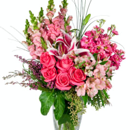 Pink roses and lilies arranged in a clear glass vase